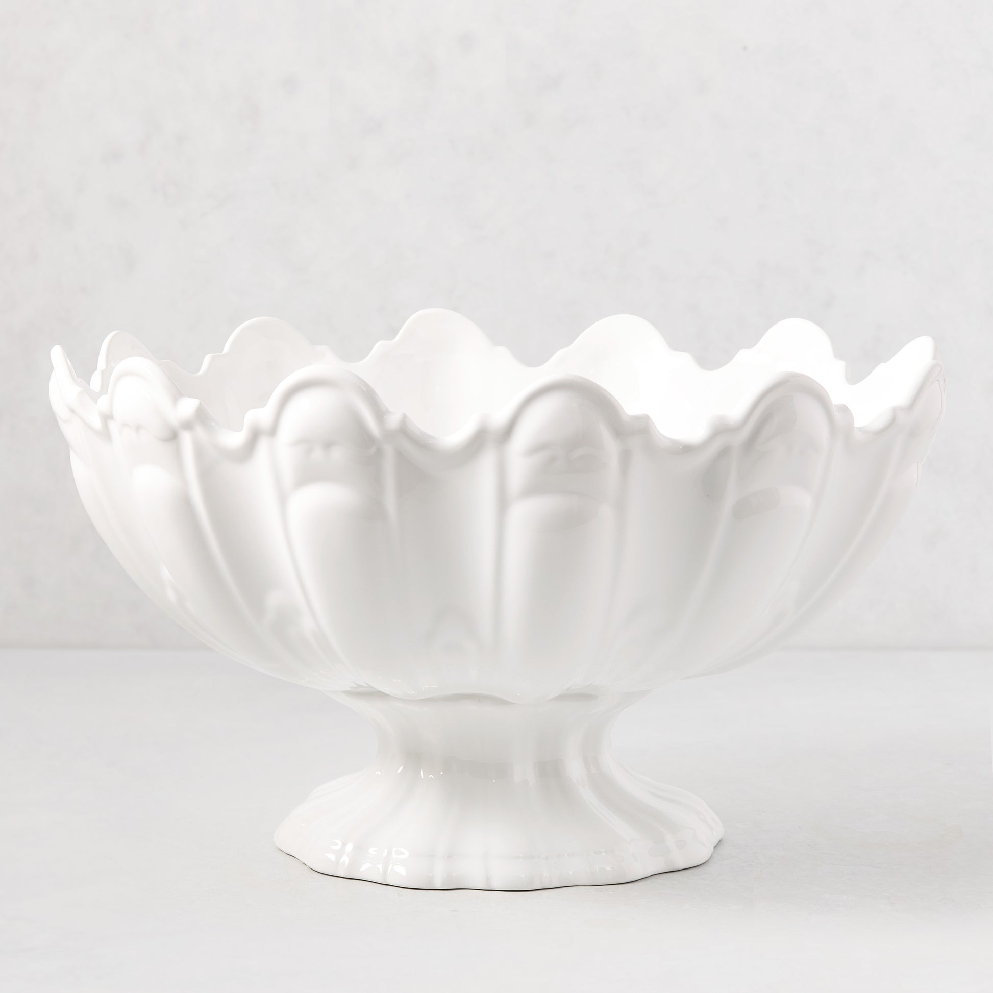 White ceramic scallop serve bowl, 17"Dia. x 9"H, with a fluted base and wavy rim.