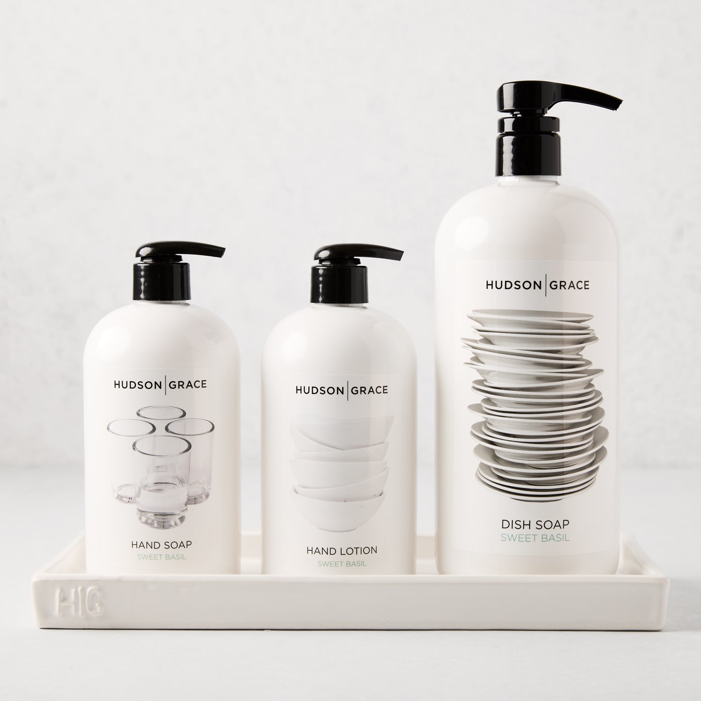 White ceramic tray with "HG" monogram, holding three Hudson Grace cleaning bottles.