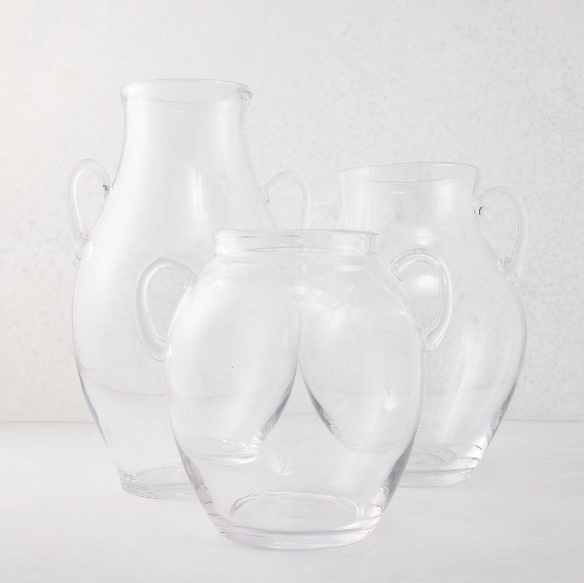 Three clear recycled glass confit vases with decorative handles, varying in size.