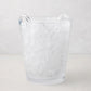 Large clear handblown glass ice bucket with two handles, filled with ice.