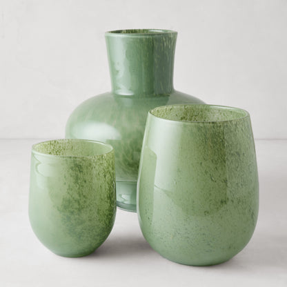 Three handblown opaque green glass barrel vases: one large, two smaller.