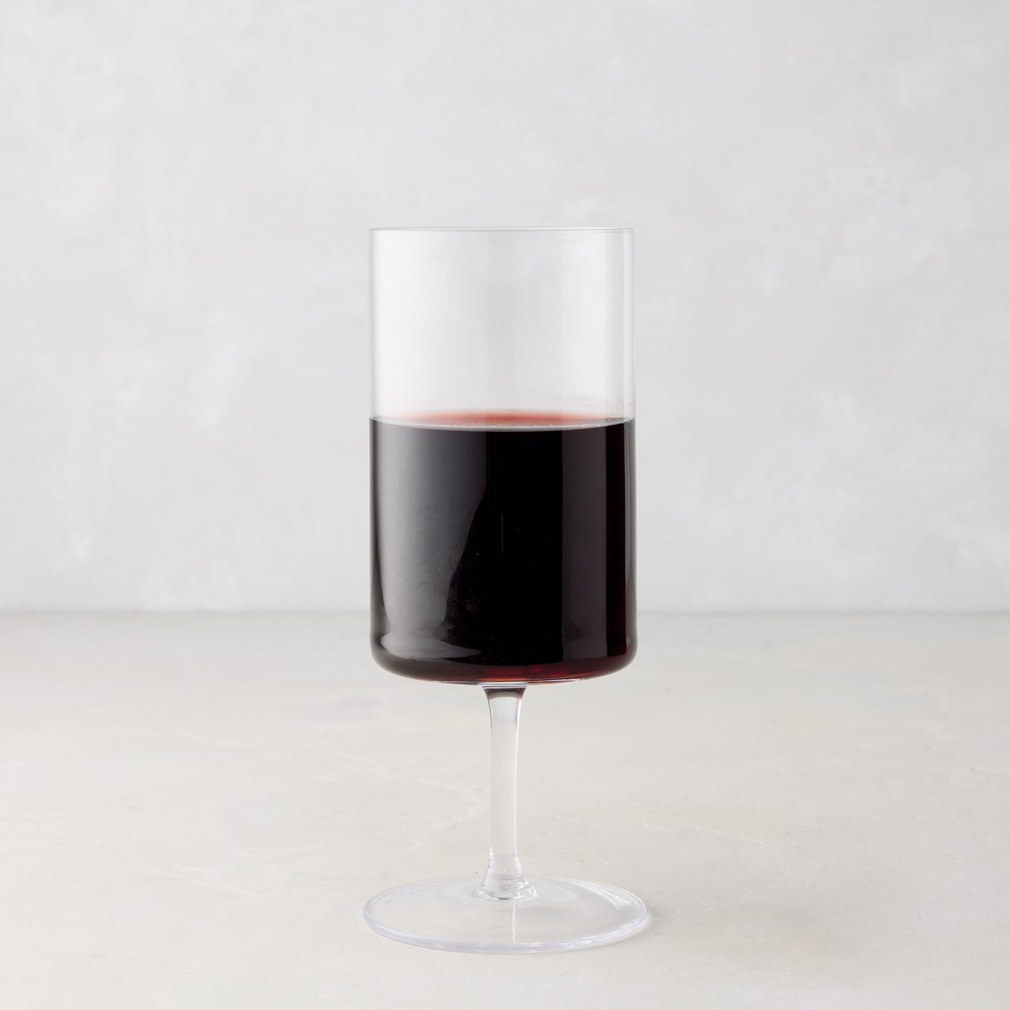 Large Hugo Stemmed Wine Glass, clear glass with red wine, modern sleek design.