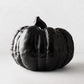 Large matte black ceramic pumpkin decor with a textured, ribbed surface on a white background.