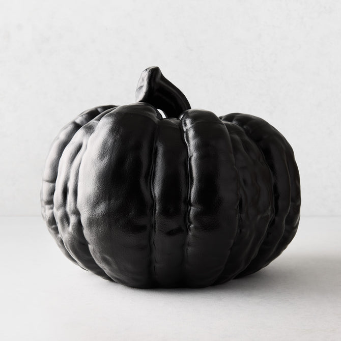 Large matte black ceramic pumpkin decor with a textured, ribbed surface on a white background.