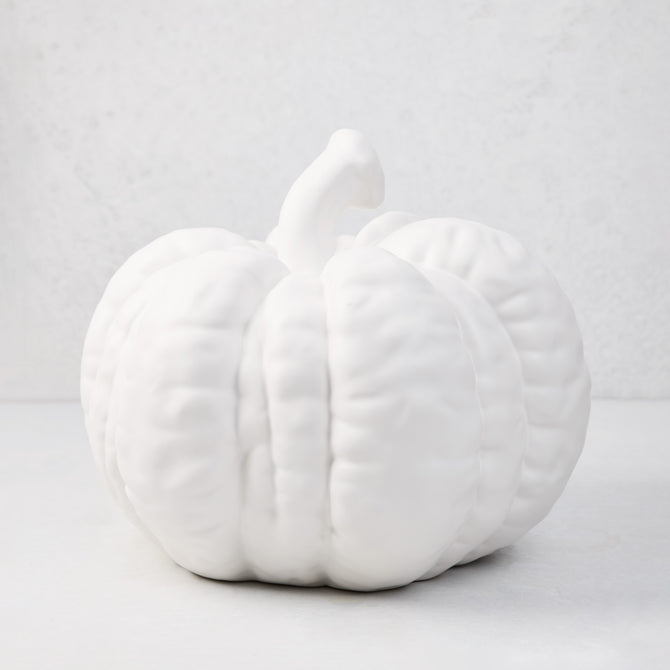 Large matte white ceramic pumpkin, 12"H x 10"Dia, with a short stem and ribbed texture.
