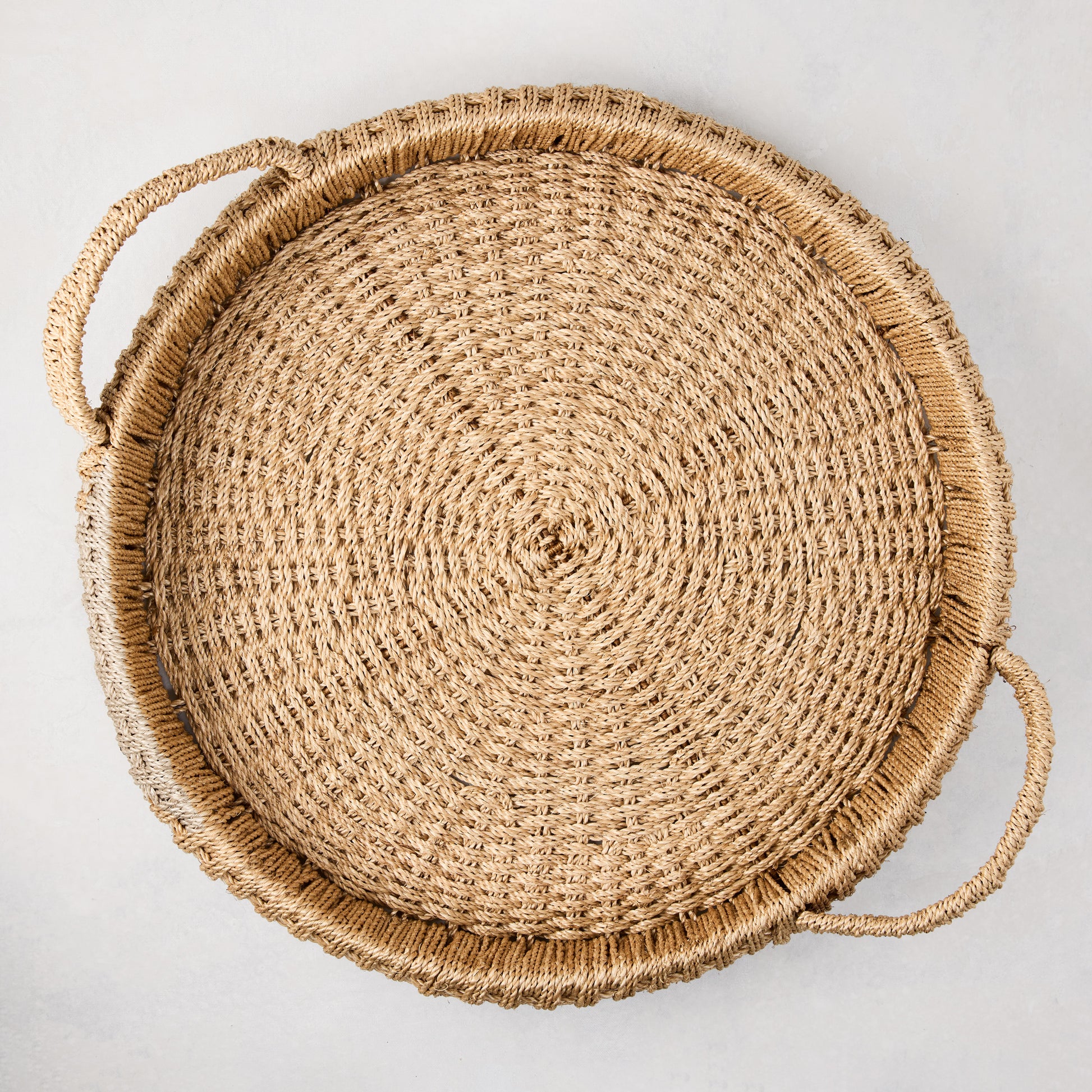 Large round woven abaca handled tray, natural brown, 20" diameter, with integrated handles.