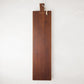 Long, dark brown European pine serving plank with a handle and rope for hanging.
