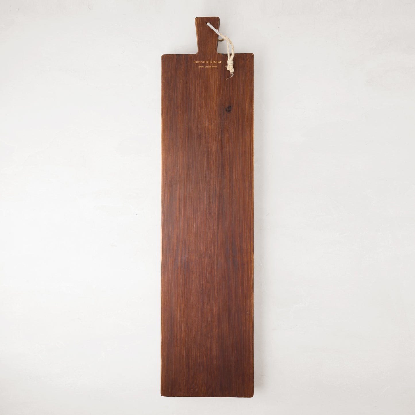 Long, dark brown European pine serving plank with a handle and rope for hanging.