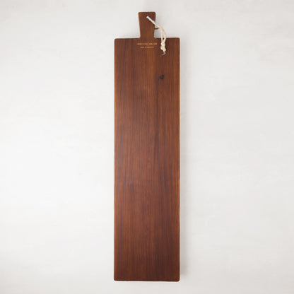 Long, dark brown European pine serving plank with a handle and rope for hanging.