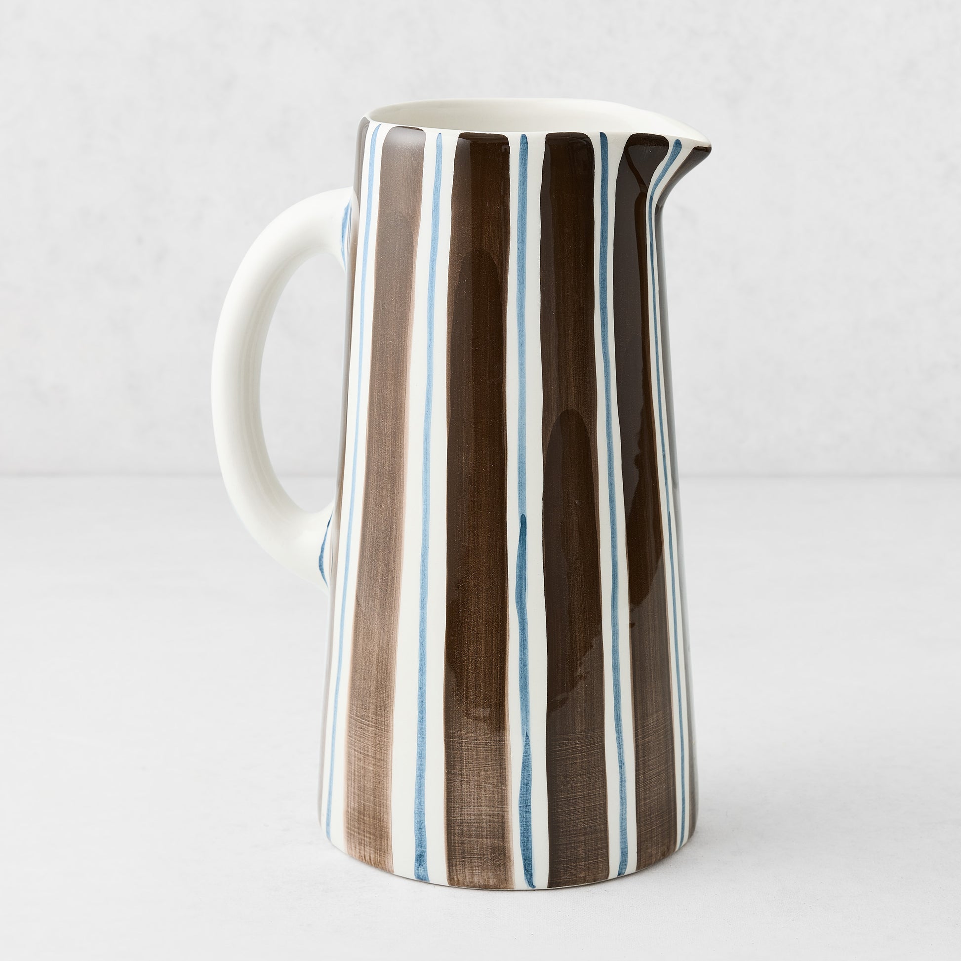Large Italian ceramic pitcher with hand-painted navy and chocolate brown vertical stripes on a white glazed finish.