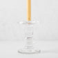 Clear glass taper candleholder with ridged design, holding a cream candle.