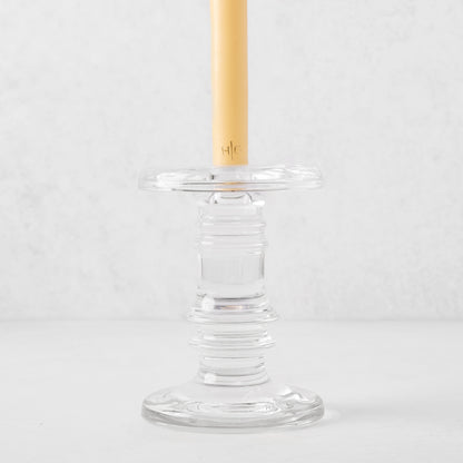 Clear glass taper candleholder with ridged design, holding a cream candle.