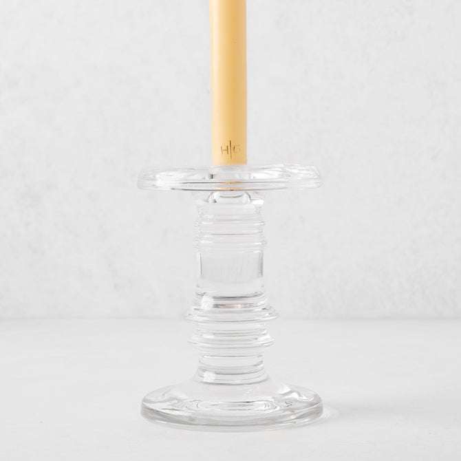 Clear glass taper candleholder with ridged design, holding a cream candle.