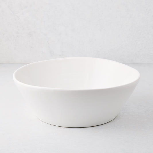 Large white spiral ceramic serve bowl with high edges on a light background.