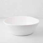 Large white spiral ceramic serve bowl with high edges on a light background.