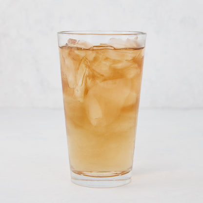 Tall, clear Hudson Grace glass filled with ice and a brown beverage.