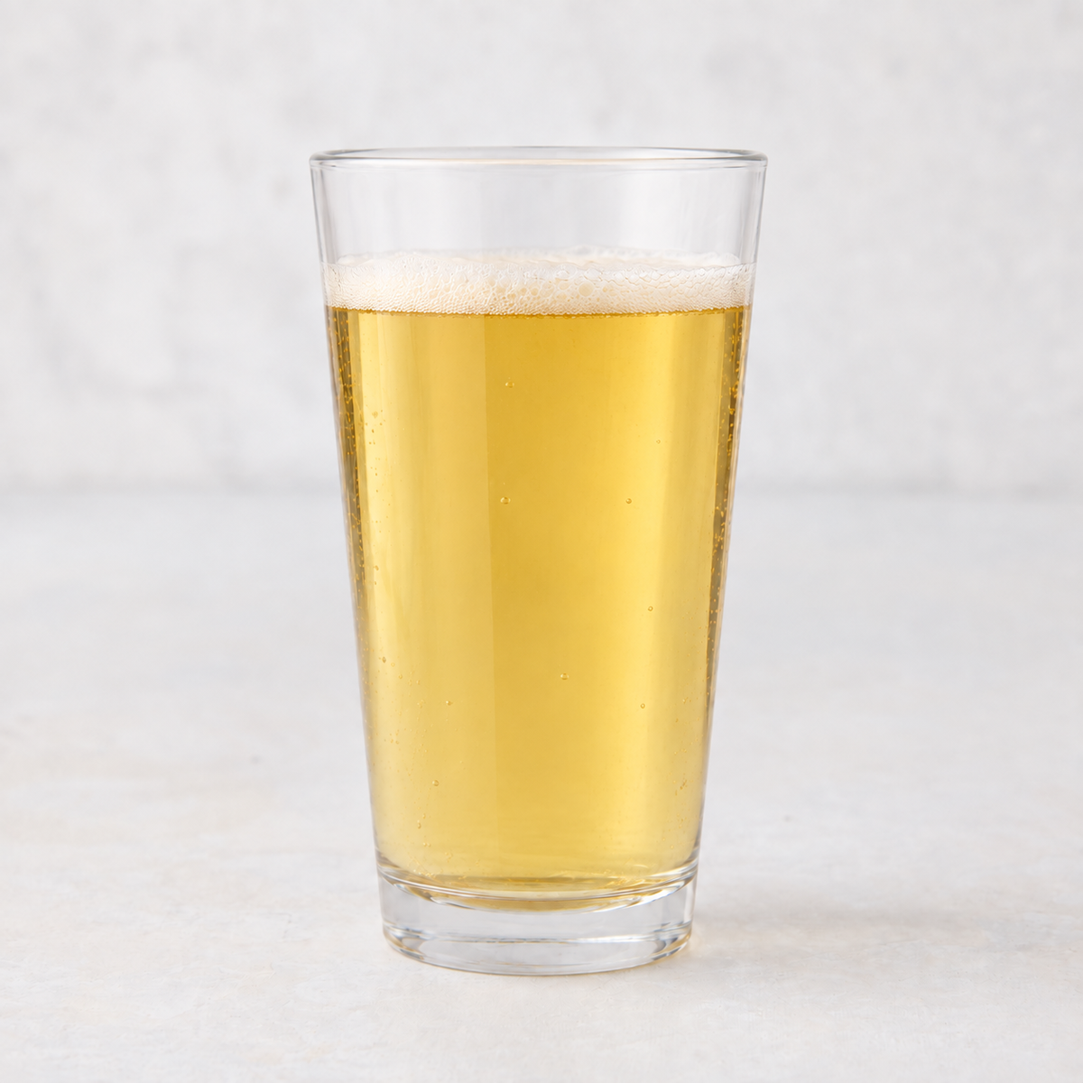 Clear 12oz tall drinking glass filled with golden beer, featuring a thick-walled base on a white surface.