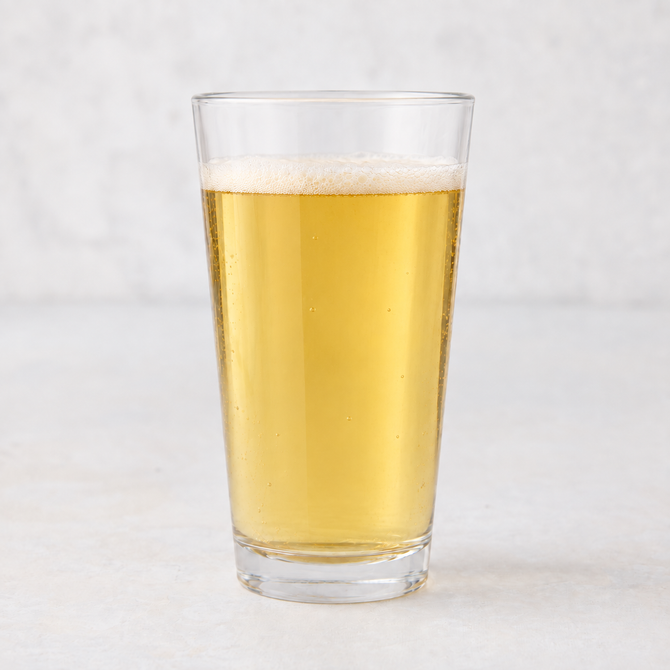 Clear 12oz tall drinking glass filled with golden beer, featuring a thick-walled base on a white surface.