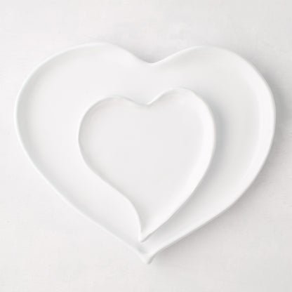 Two white ceramic heart dishes, one large and one small, nested together.