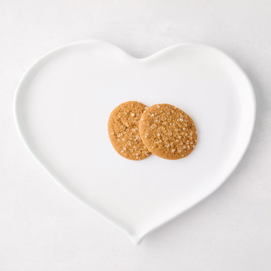 Large white ceramic heart dish with two sugar-dusted cookies.