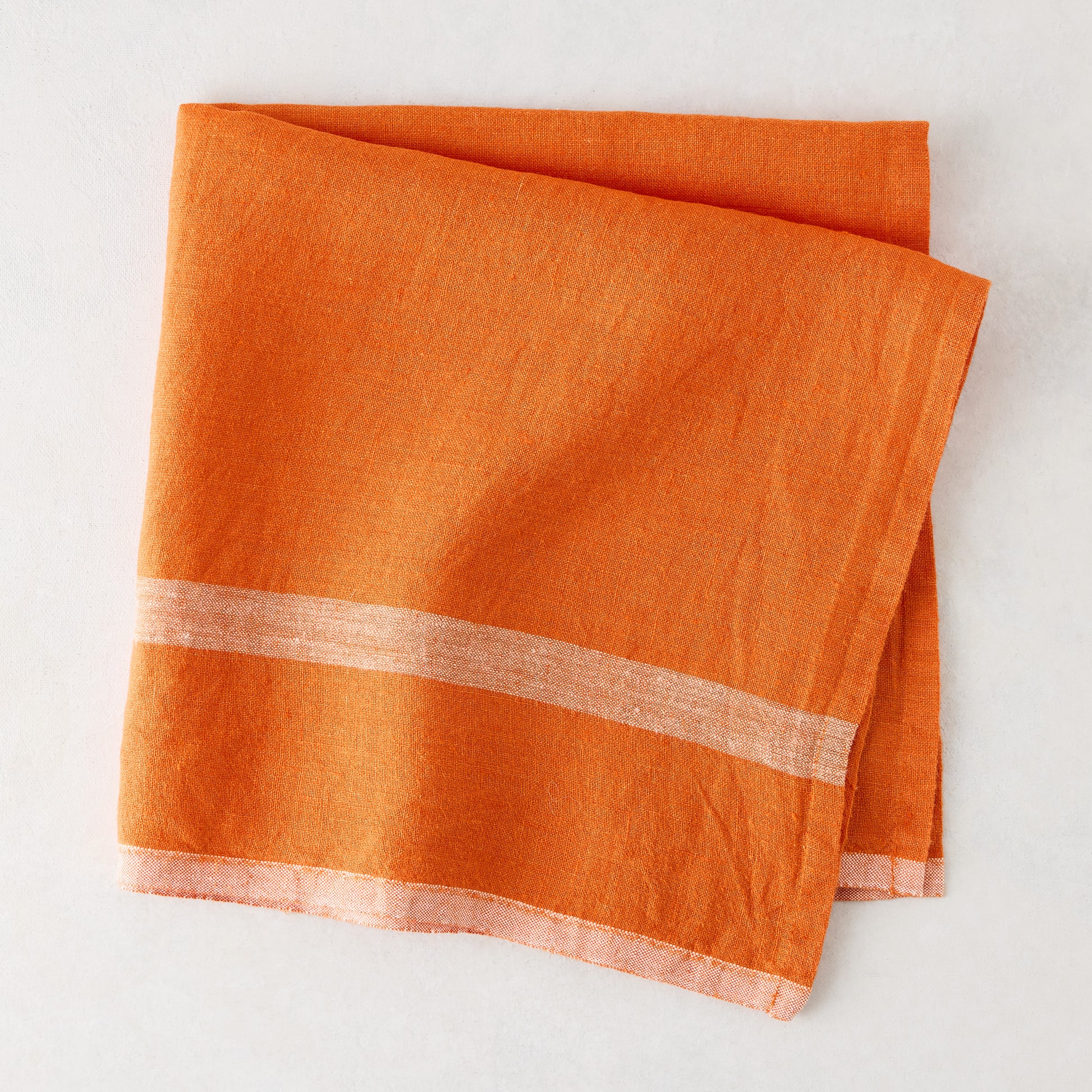 Laundered bright orange linen napkin, 22" square, with paler horizontal stripes.