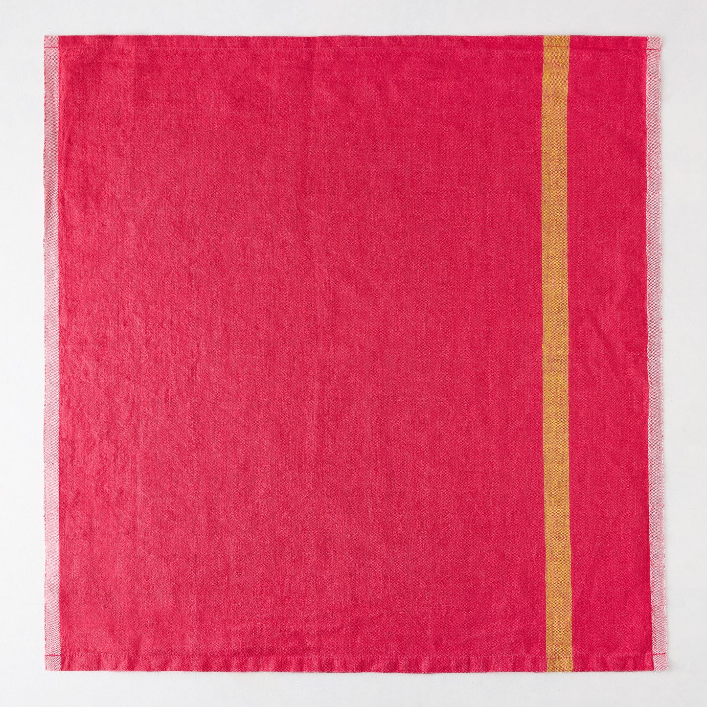 Laundered bright pink linen napkin with a single vertical gold stripe and paler striped edges.