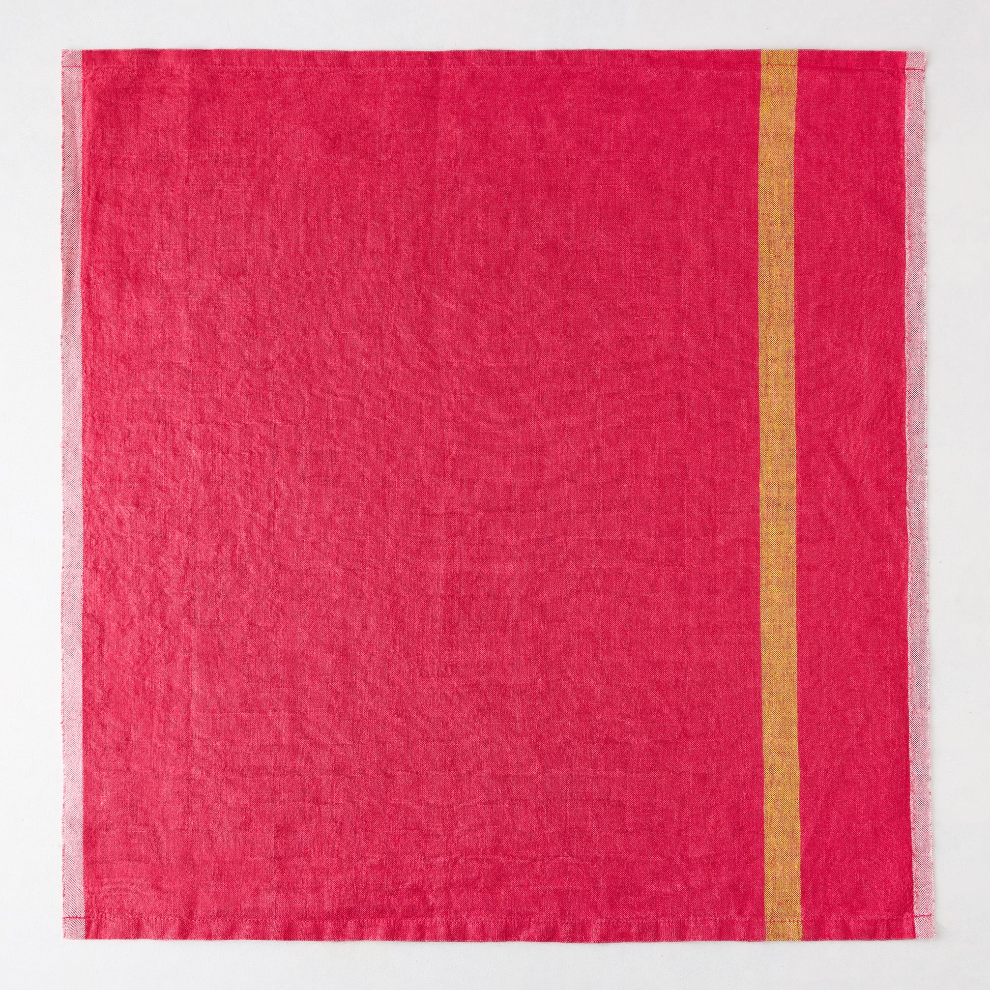 Laundered bright pink linen napkin with a single vertical gold stripe and paler striped edges.