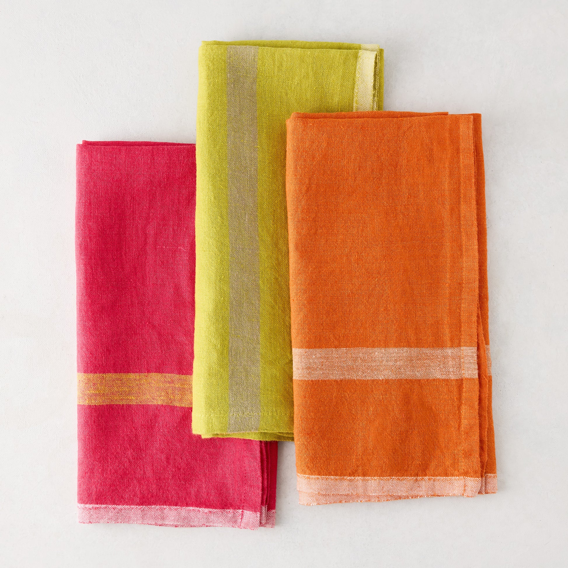 Laundered lime green, pink, and orange linen napkins with paler stripes.