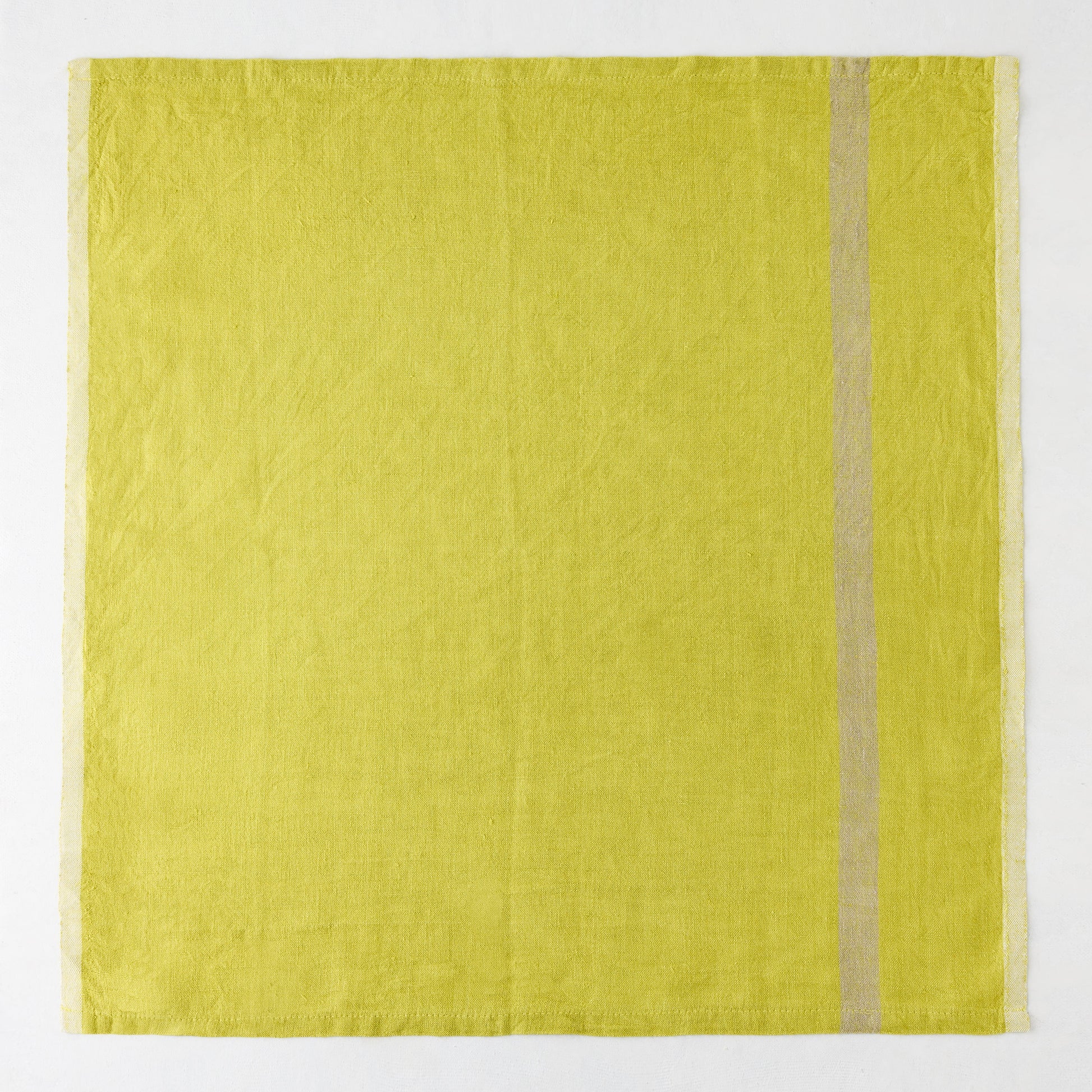 Laundered lime green linen napkin with a paler stripe on the right and a thin stripe on the left.