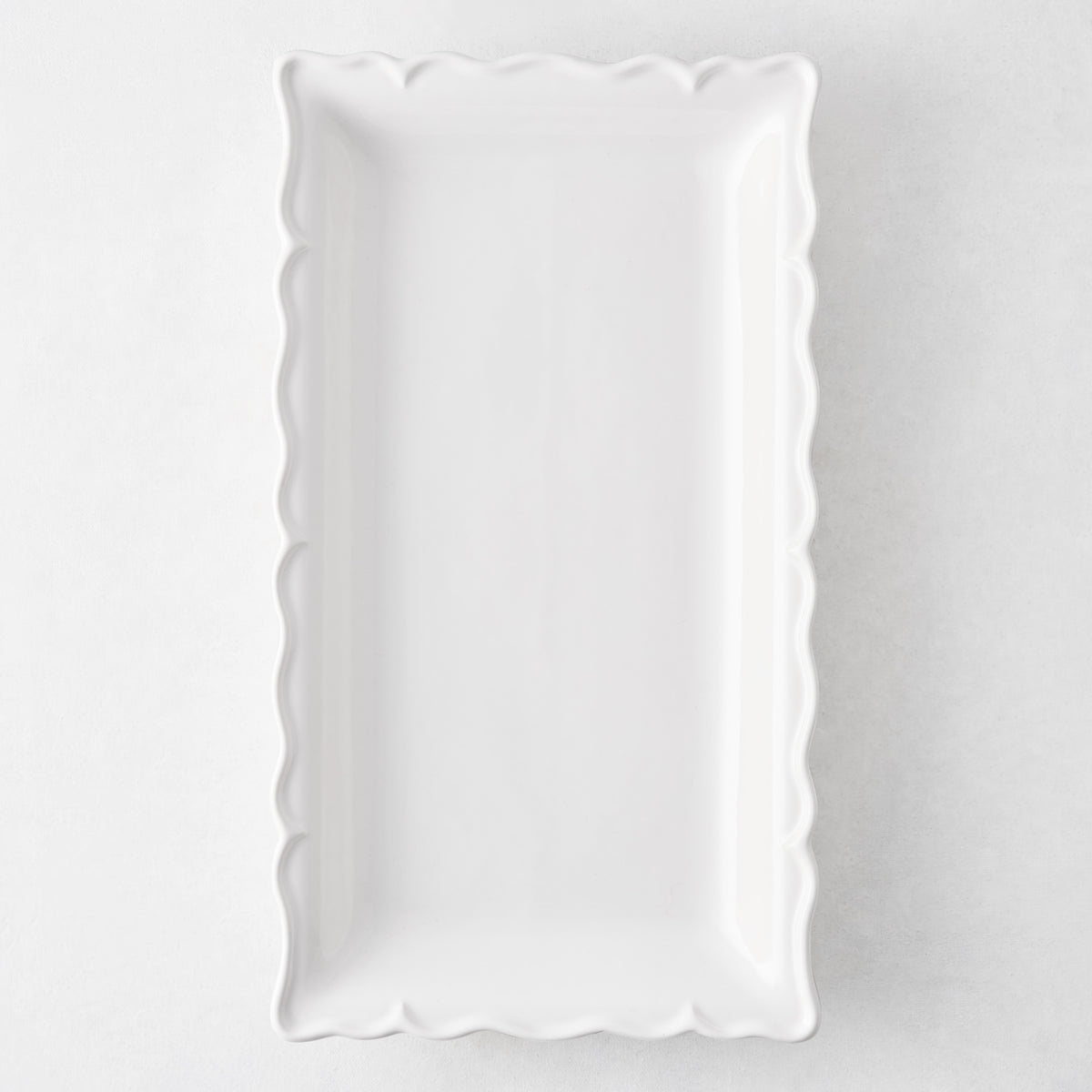 Rectangular white ceramic serve platter with a decorative scalloped edge, 13.77 inches long, made in Italy.