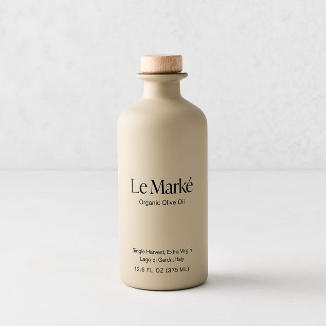 Le Marké olive oil in a matte beige ceramic bottle with a wooden cork stopper, 12.6 oz size.