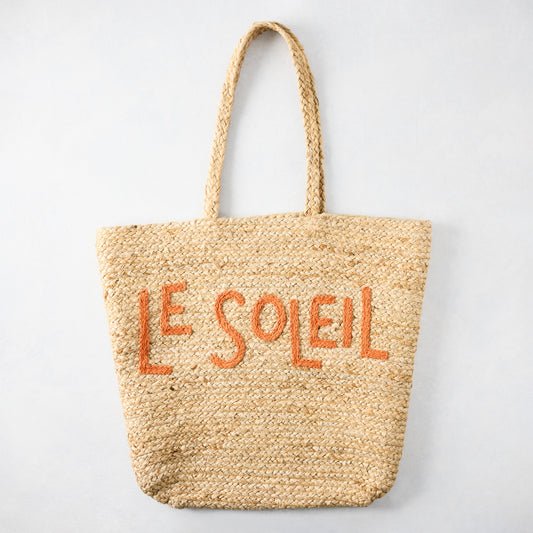 Natural jute woven tote bag with "LE SOLEIL" embroidered in orange.