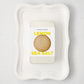 White rectangular Colette Platter with curved edges holding a silver tin of Hudson Grace Lemon Sea Salt cookies.