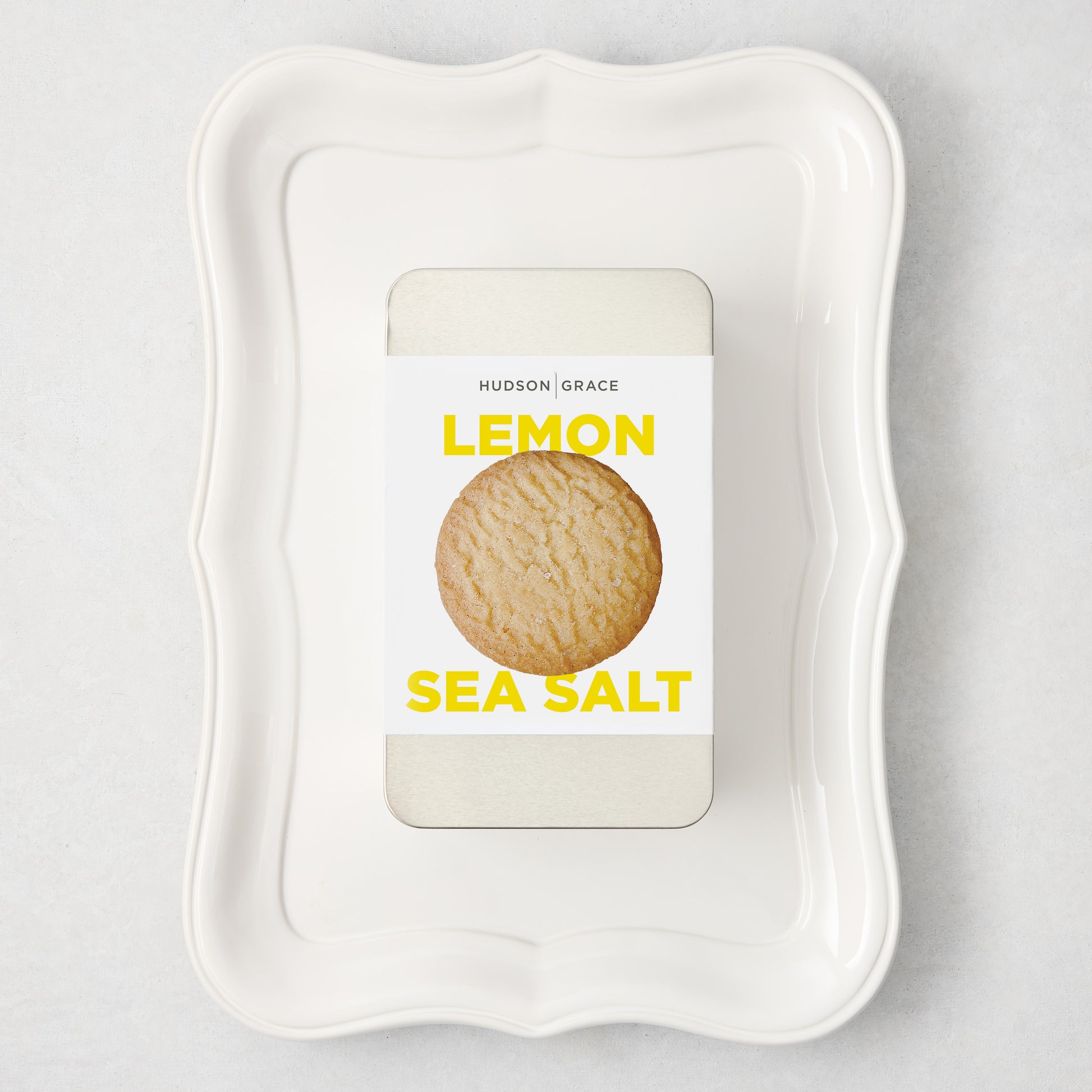 White rectangular Colette Platter with curved edges holding a silver tin of Hudson Grace Lemon Sea Salt cookies.