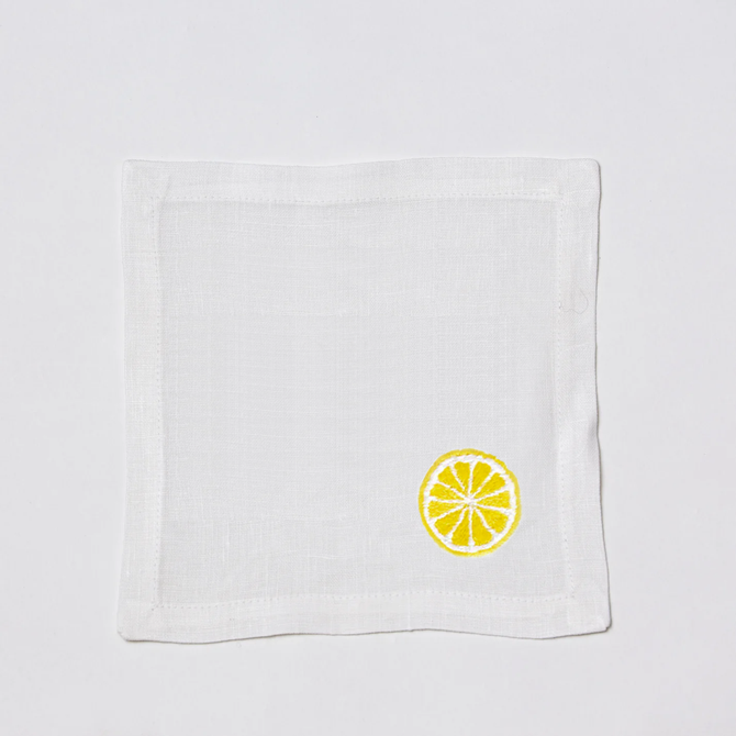 White linen cocktail napkin coaster with embroidered yellow lemon slice.