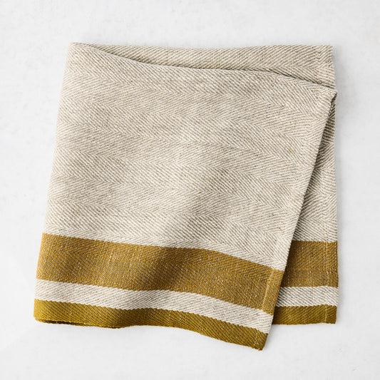 Lexington Gold Stripe Border Napkin, natural linen-cotton blend with gold striped edges, folded.