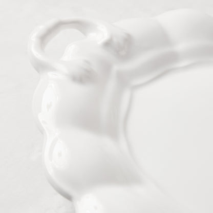 White ceramic oval serving platter with decorative handles and French detailing.