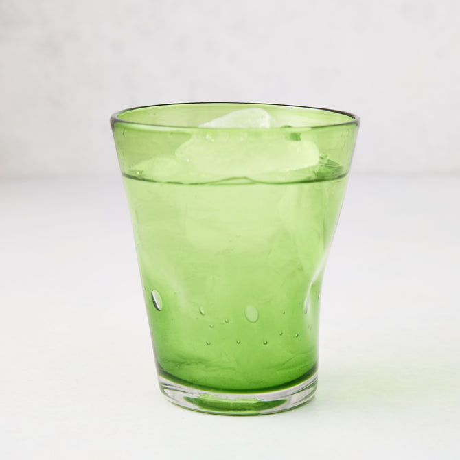 Light green Henri mouth-blown glass, 8 oz, with ice and water, showing unique imperfections and air bubbles.