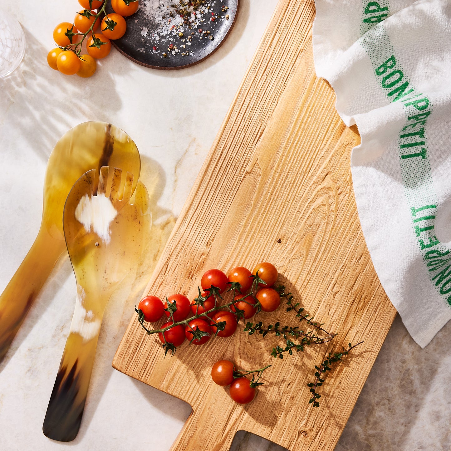 Light Horn Salad Server Set: 12" natural water buffalo horn servers with unique grain, next to cherry tomatoes on a wood board.