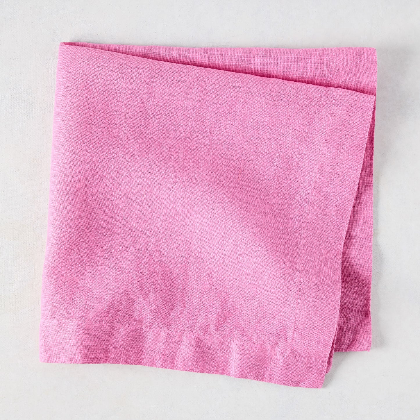 Lily HG Signature hand-dyed pink linen napkin, folded, 22-inch square.