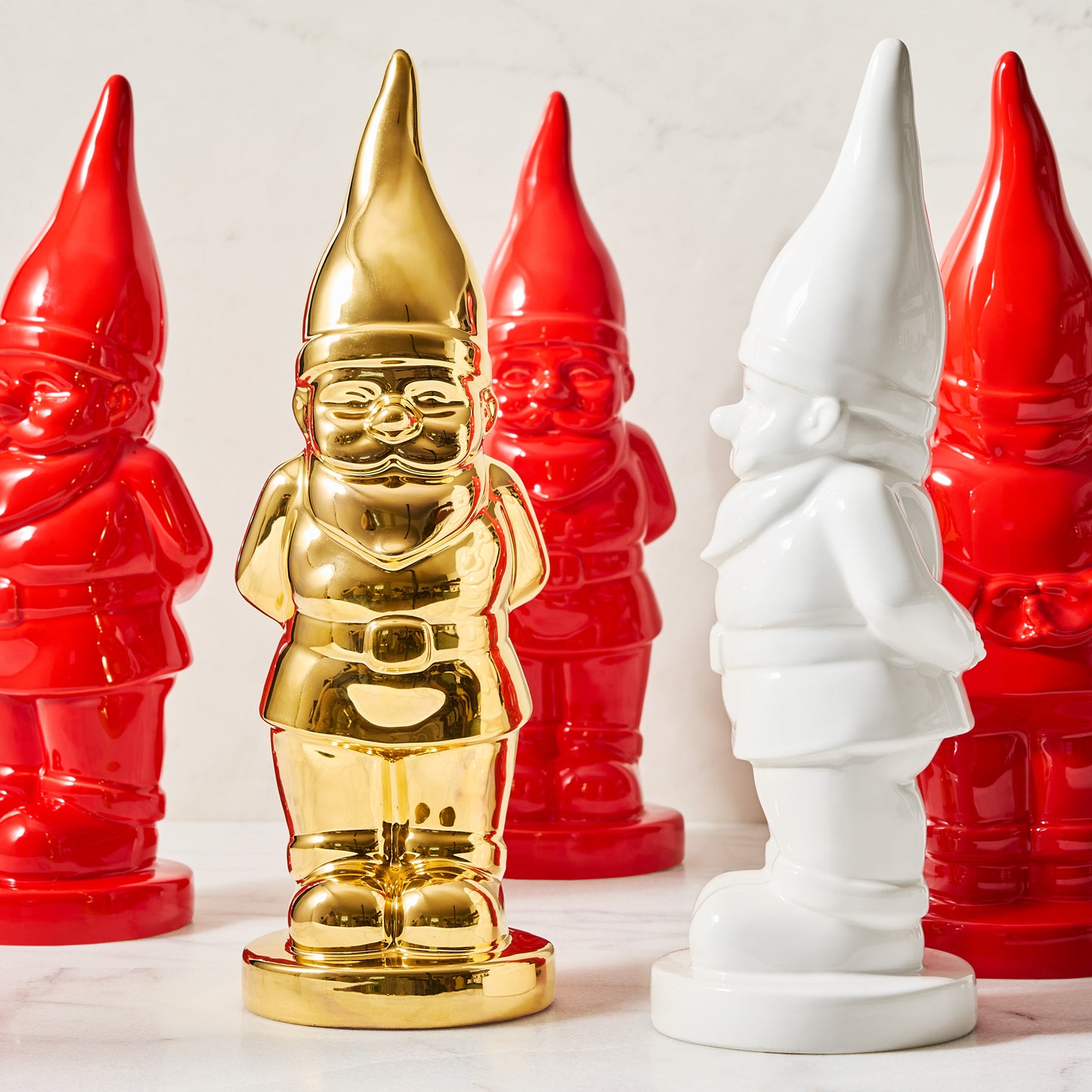 Limited Edition Gold Ceramic Holiday Gnome, surrounded by red and white ceramic gnomes.