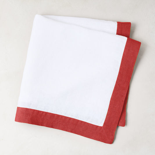 White linen napkin with a flame red border, folded.