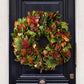 24-inch holiday wreath featuring fresh magnolia leaves, red berries, Carolina Sapphire greenery, and miniature pinecones.