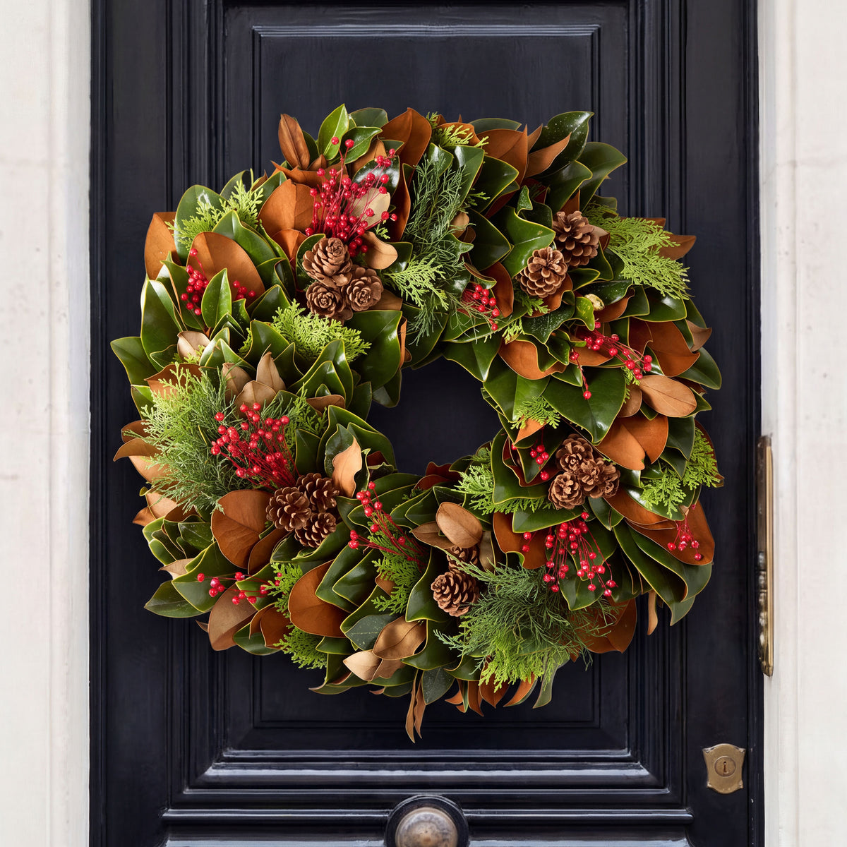 24-inch holiday wreath featuring fresh magnolia leaves, red berries, Carolina Sapphire greenery, and miniature pinecones.