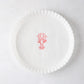 White round parchment liner with ruffled edges and a red lobster illustration in the center.