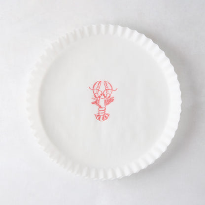 White round parchment liner with ruffled edges and a red lobster illustration in the center.