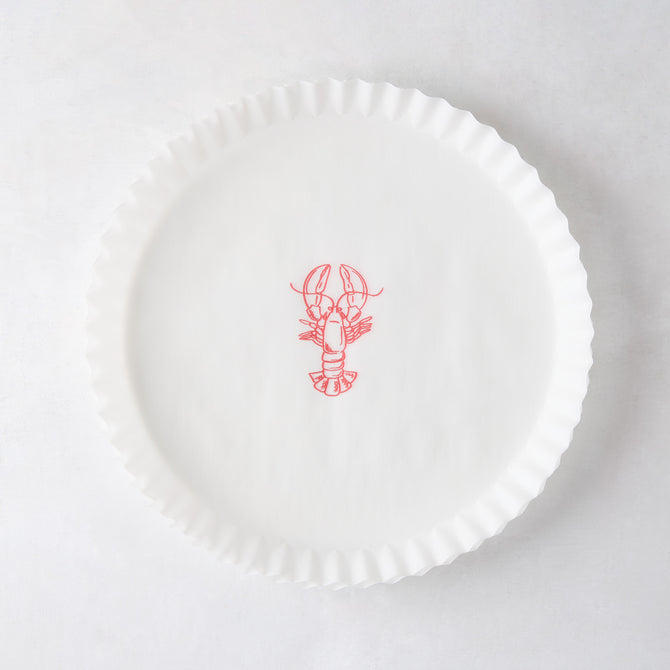 White round parchment liner with ruffled edges and a red lobster illustration in the center.