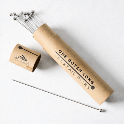 Set of 12 long 8" stainless steel cocktail picks with ball tops in a brown cardboard tube.