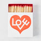 Oversized white matchbox with a red heart and "LOVE" text, filled with long wooden matches with red tips.