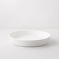 White, round Luce Small Ceramic Serving Dish, 11.5" diameter, with a minimalistic design.